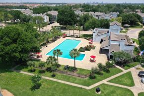 Houston apartment for rent - A swimming pool surrounded by a grassy area and trees.