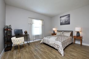 Houston apartment for rent - A bedroom with a bed, chair, and a painting on the wall.