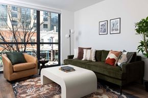 Washington apartment for rent - A living room with a green couch, a white coffee table, and a large window.