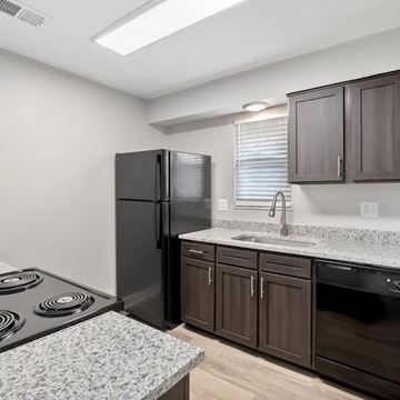 Lexington apartment for rent - A black refrigerator is in a kitchen with brown cabinets.