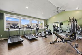 Nampa apartment for rent - A spacious home gym with a variety of exercise equipment and a view of the outside through the windows.