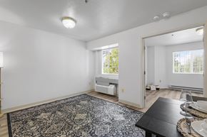 Garden City apartment for rent - the living room and dining room of a house with white walls and a black rug