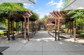 Garden City apartment for rent - a covered walkway with benches and trees in a park