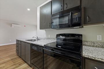 Boise apartment for rent - A black microwave is mounted above a black stove in a kitchen.