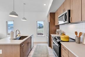 Missoula apartment for rent - A modern kitchen with wooden cabinets and a black stove top oven.