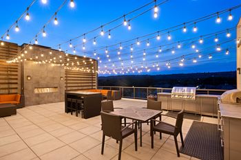 A patio with a table and chairs under lights