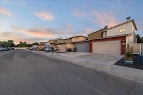 Meridian townhouse for rent - A parking lot with a building and a garage door in the background. at Verraso Village Apartments, Idaho