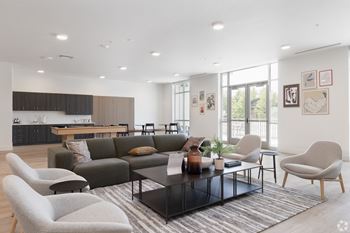 A modern living room with a grey sofa, a black coffee table, and a grey armchair.