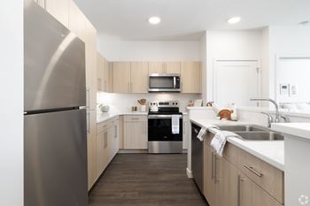 A modern kitchen with a stainless steel refrigerator and wooden cabinets.