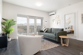 A living room with a green couch and a white ottoman.
