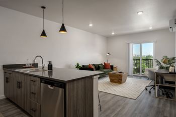 An open kitchen and living room in a home with white walls and wood floors