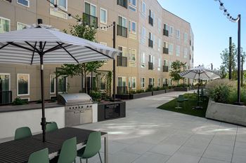 A patio with tables and umbrellas in front of an apartment building