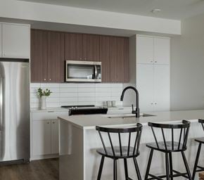 Bozeman apartment for rent - a kitchen with white cabinets and a white island with two black bar stools