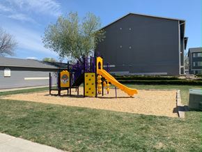 Boise apartment for rent - a playground with a slide and swings in front of a building