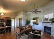 Bozeman apartment for rent - A living room with a couch, a coffee table, a fireplace, and a ceiling fan at Saddleview Apartment Homes, Montana, 59715.