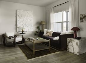 Bozeman apartment for rent - A living room with a white chair, a black couch, a coffee table, and a large painting on the wall.