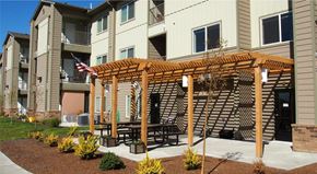 Post Falls apartment for rent - an outdoor patio with a wooden pergola in front of an apartment building