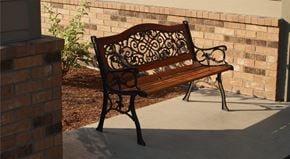Post Falls apartment for rent - a wood and wrought iron park bench sitting in front of a brick wall