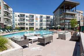 Aurora apartment for rent - A pool area with lounge chairs and umbrellas in front of apartment buildings.