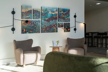 Boise apartment for rent - A living room with a green couch, two chairs, and a large painting on the wall.