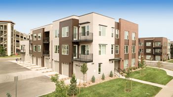 A rendering of a new apartment building with green grass and a sidewalk