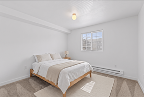 Boise apartment for rent - A bedroom with a bed, nightstand, and window.