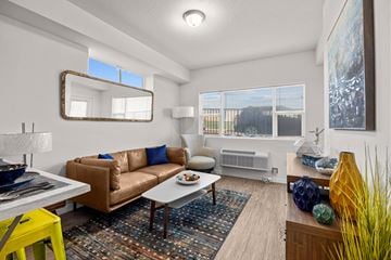 Missoula apartment for rent - A living room with a brown couch and a yellow stool.