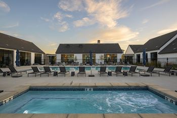 A swimming pool with chairs around it and a building in the background