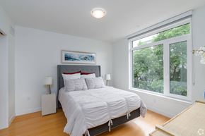 Cambridge apartment for rent - A bedroom with a large bed and a window overlooking trees  at 605 Concord at Fresh Pond Apartments, Massachusetts