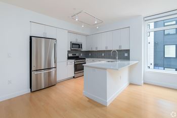 A kitchen with a refrigerator, oven, and microwave.