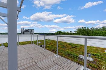 A wooden deck with a metal railing overlooks a green field.