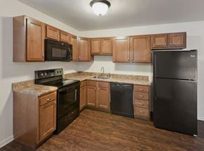 Schenectady apartment for rent - an empty kitchen with black appliances and wooden cabinets