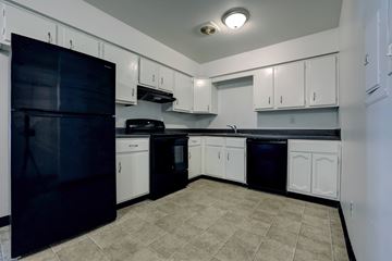 Schenectady apartment for rent - A kitchen with black appliances and white cabinets.