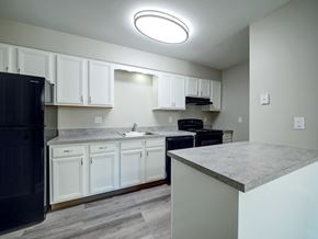 Troy apartment for rent - A kitchen with white cabinets and a black fridge.