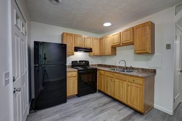 Gansevoort apartment for rent - A kitchen with wooden cabinets and a black refrigerator.