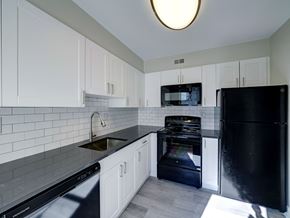 Latham apartment for rent - A black refrigerator sits in a kitchen with white cabinets and a black dishwasher.