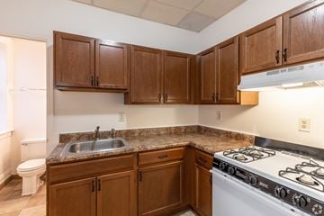 Albany apartment for rent - A kitchen with a white stove top oven and brown cabinets.