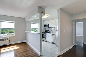 Wood-Ridge apartment for rent - A kitchen with white cabinets and a window overlooking a green landscape.
