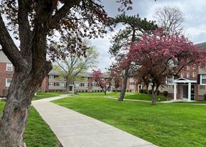 Menands apartment for rent - a sidewalk leads through a grassy area in front of a brick building