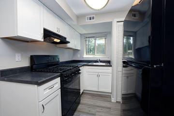 Coram apartment for rent - A kitchen with black appliances and white cabinets.