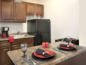 Rahway apartment for rent - A kitchen with a black refrigerator and a table set for two.