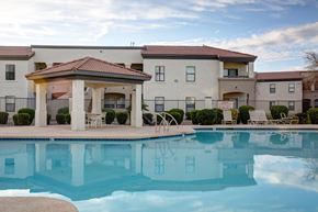 Glendale apartment for rent - A swimming pool in front of a building with a patio and chairs.