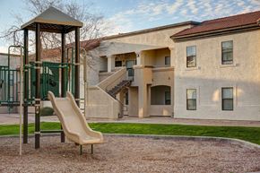 Glendale apartment for rent - A playground with a slide and a chair in front of a building.