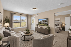 Kansas City apartment for rent - A living room with a grey couch, a coffee table, and a large window with a view of the outside.