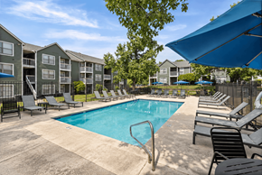 Kansas City apartment for rent - A swimming pool surrounded by lounge chairs and umbrellas in a sunny day.