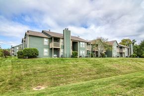 Kansas City apartment for rent - a row of green apartment buildings on top of a grass covered hill