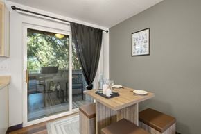 Portland apartment for rent - A dining area with a table set for two and a view of trees at Clackamas Trails Apartments, Oregon, 97222