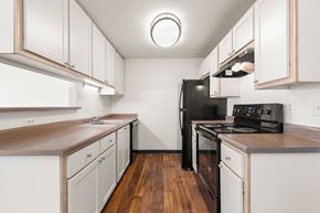 Portland apartment for rent - A kitchen with white cabinets and a black fridge at Clackamas Trails Apartments, Oregon, 97222