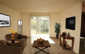 Portland apartment for rent - A living room with a brown couch, a coffee table, and a flat screen TV mounted on the wall.