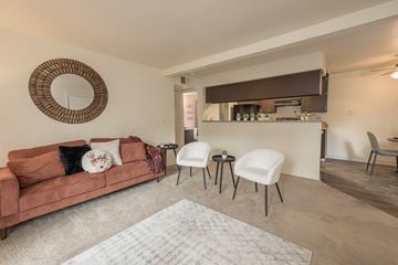 Sacramento apartment for rent - A living room with a brown couch and a round mirror on the wall.